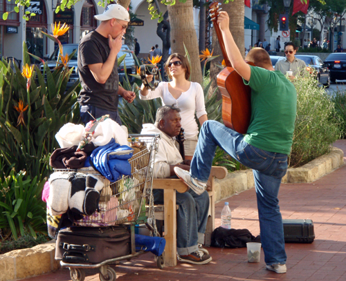 Young musicians help a homeless man collect money in State Street